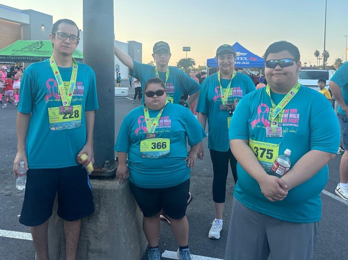 A group of people wearing medals are standing next to each other in a parking lot.