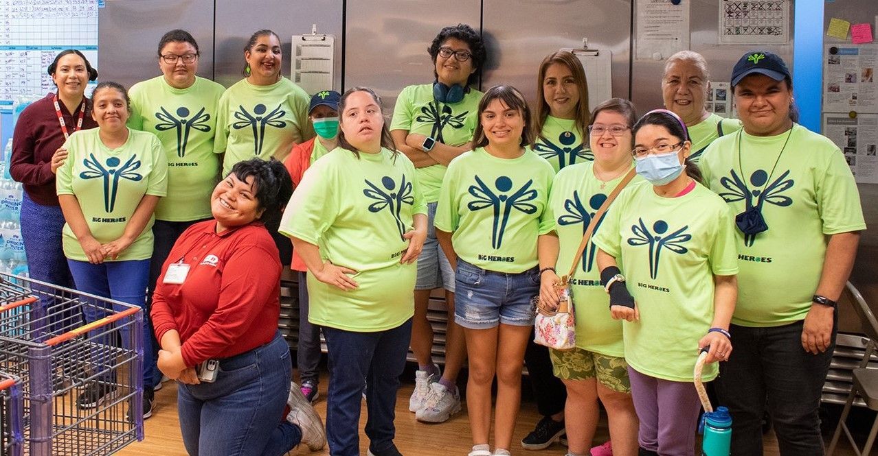 A group of people wearing green shirts are posing for a picture.