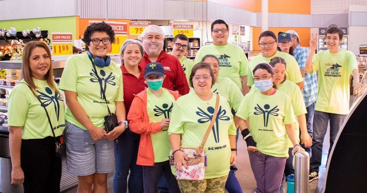 A group of people wearing green shirts and masks are posing for a picture in a store.