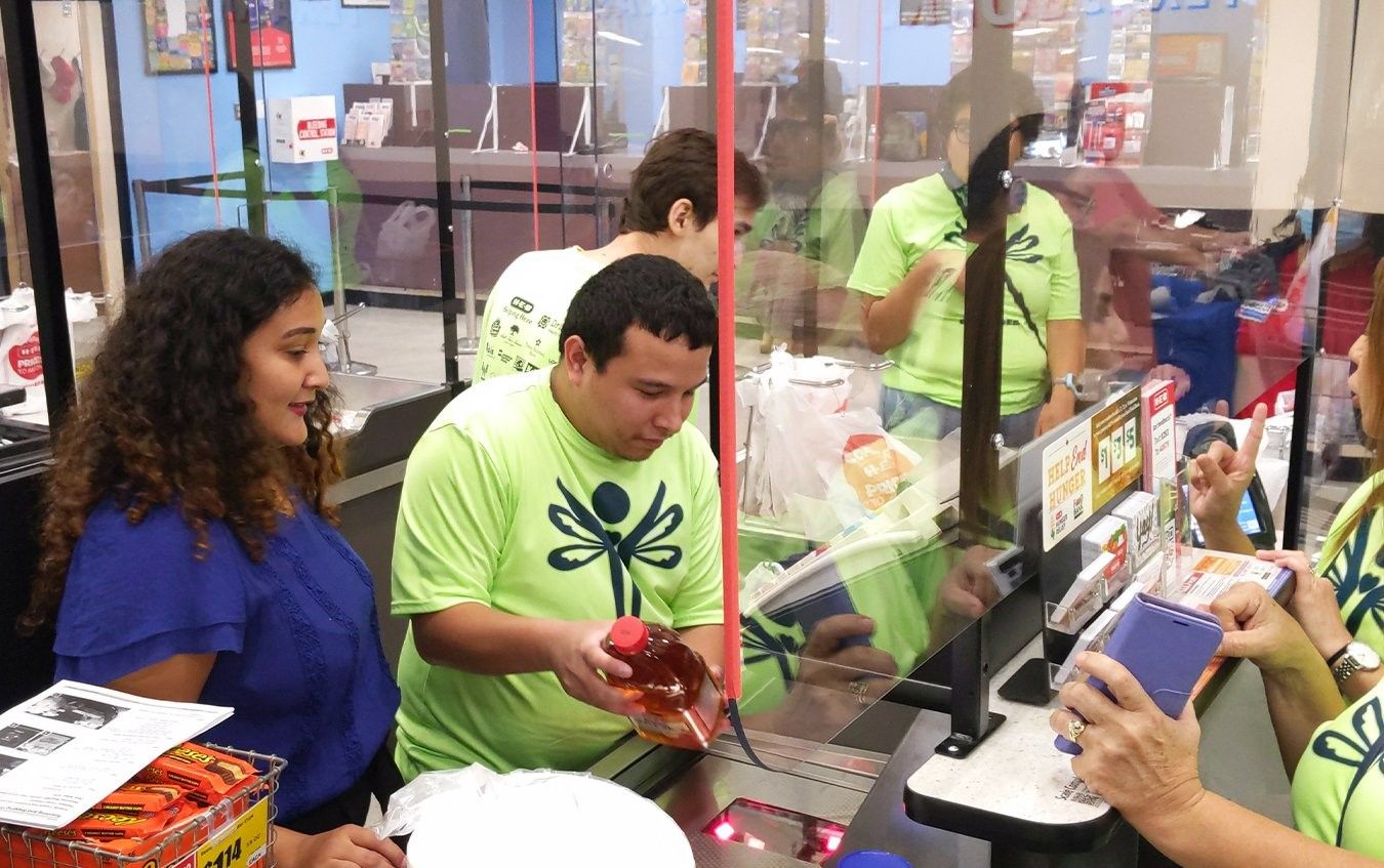 A group of people are standing around a counter in a store.