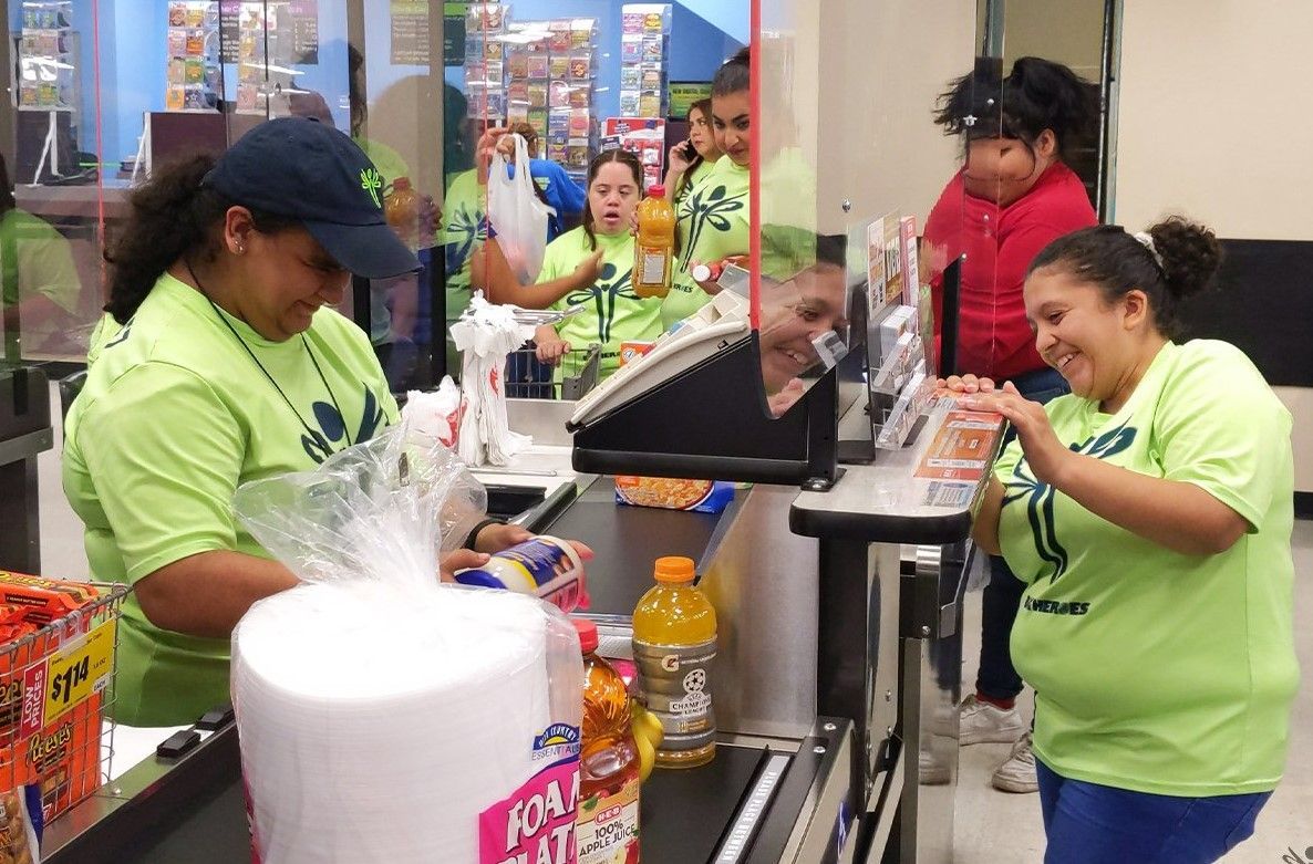 Two women in green shirts are working at a grocery store