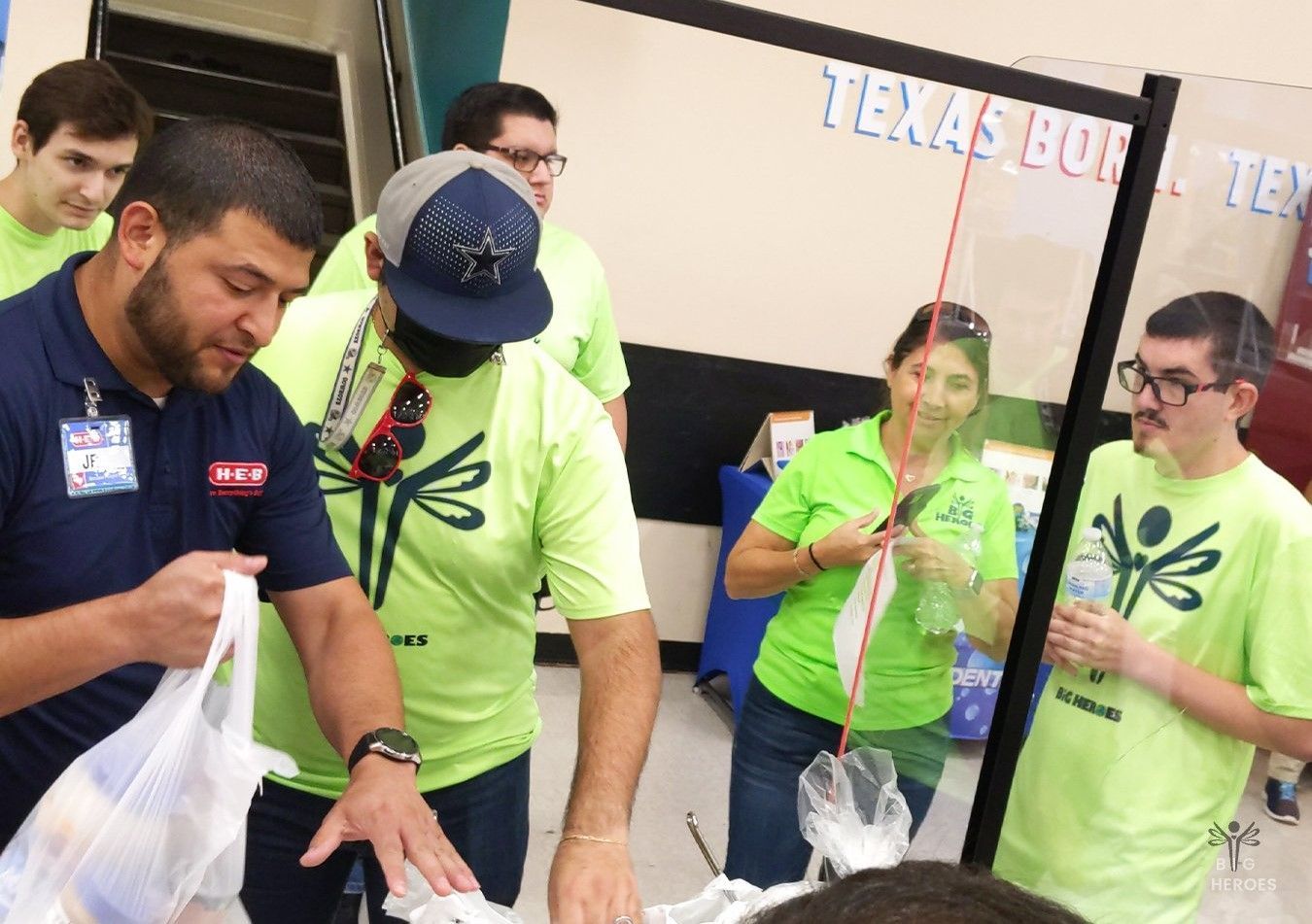 A group of people are standing around a table in front of a sign that says texas bowl