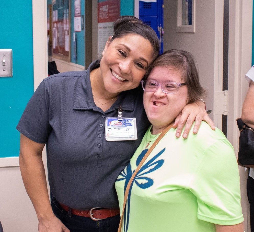 Two women are posing for a picture together in a room.