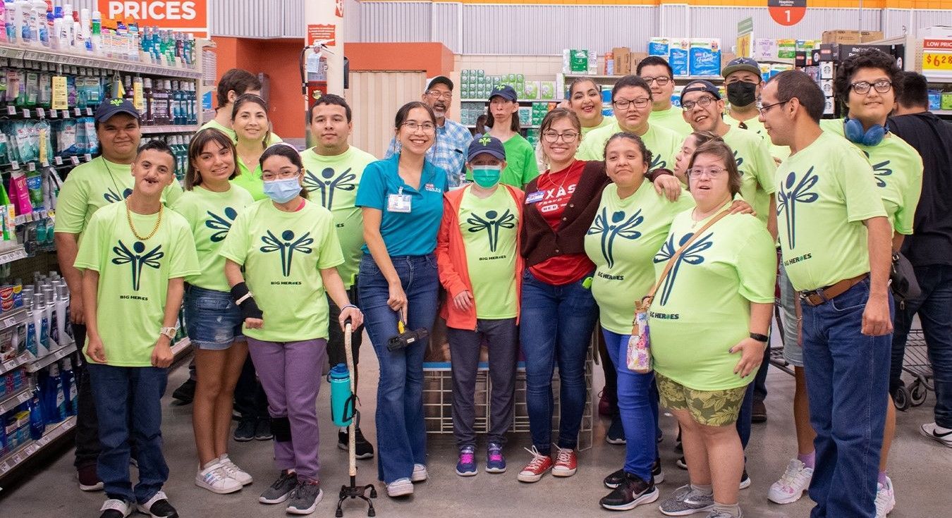 A group of people wearing green shirts are posing for a picture in a store.