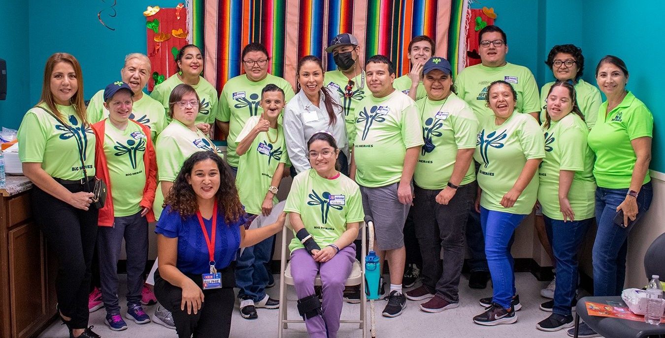 A group of people wearing green shirts are posing for a picture.
