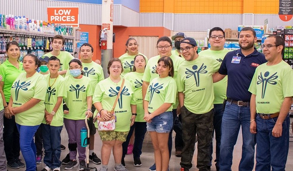 A group of people wearing green shirts are posing for a picture in a store.