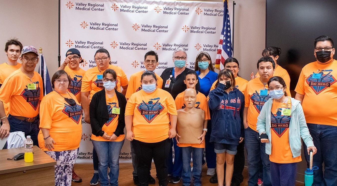 A group of people wearing masks and orange shirts are posing for a picture.
