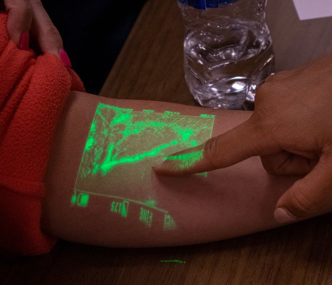 A person is pointing at a glow in the dark image on their arm