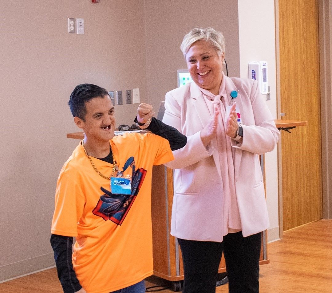 A man in an orange shirt is standing next to a woman in a pink jacket.