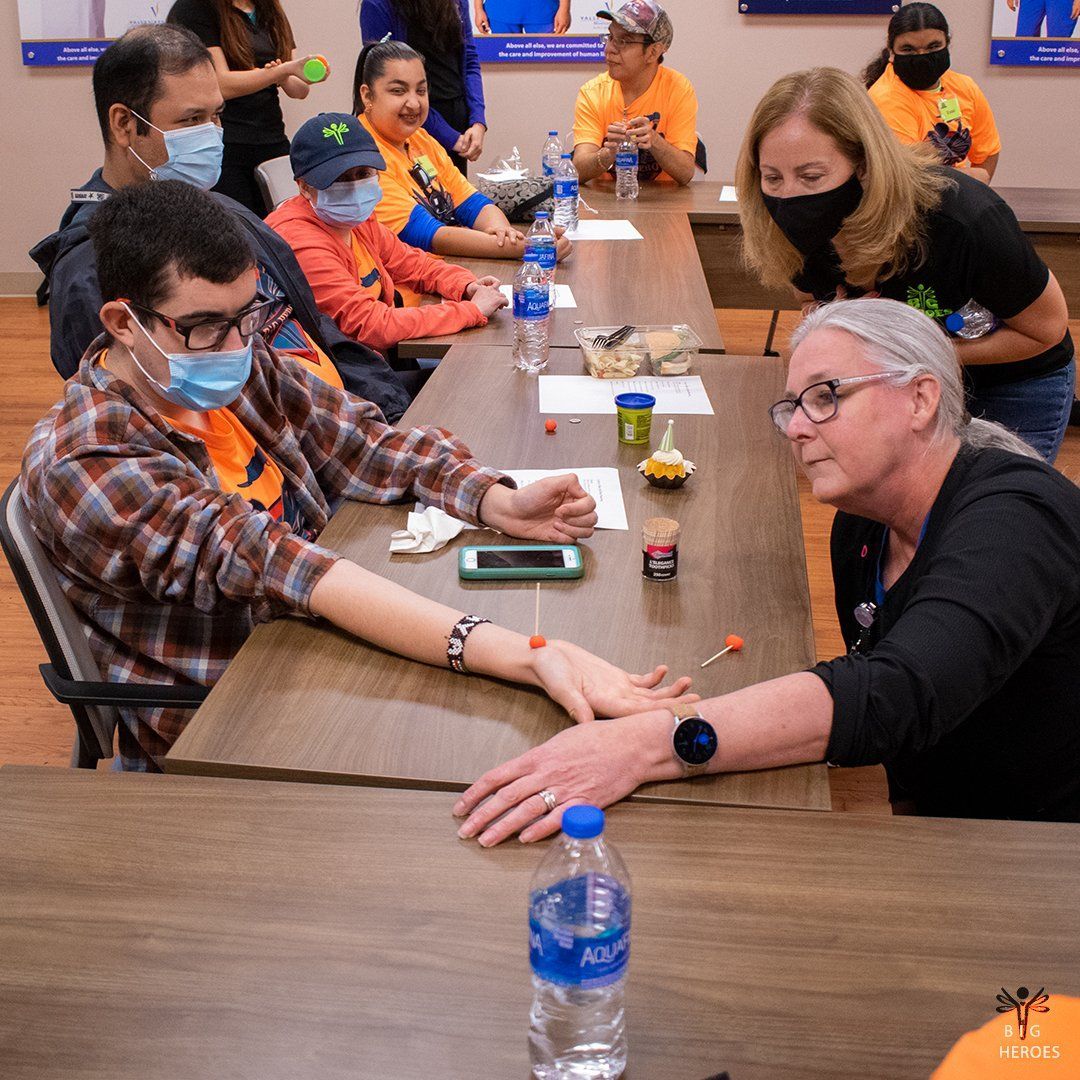 A group of people wearing face masks are sitting at a long table.