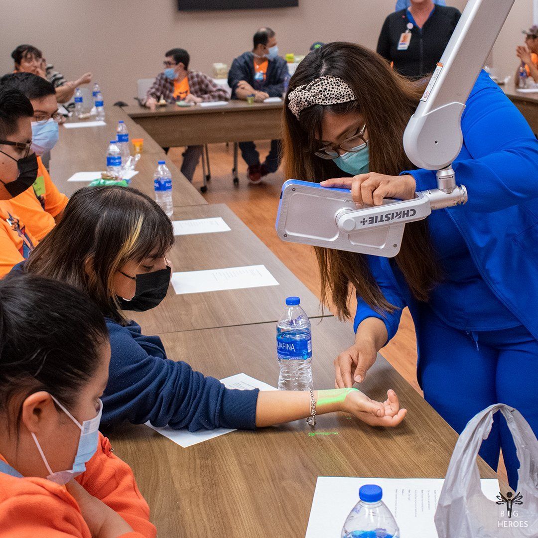 A group of people wearing face masks are sitting at tables with bottles of water.