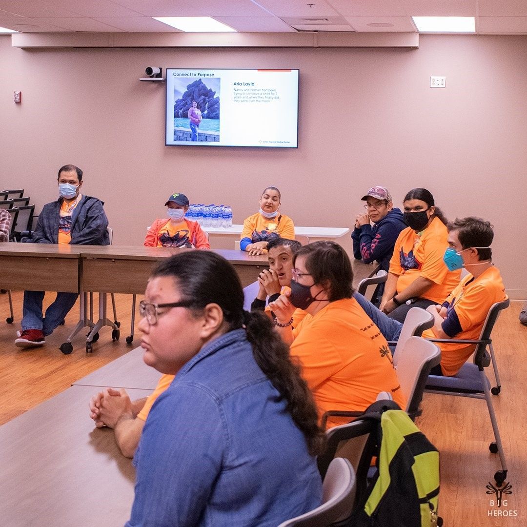 A group of people wearing masks are sitting at tables in a room.