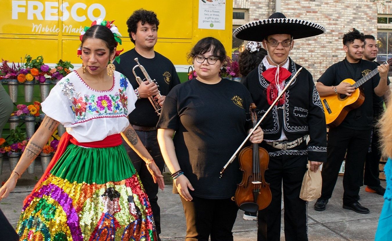 A group of people are dancing and playing instruments in front of a yellow truck.
