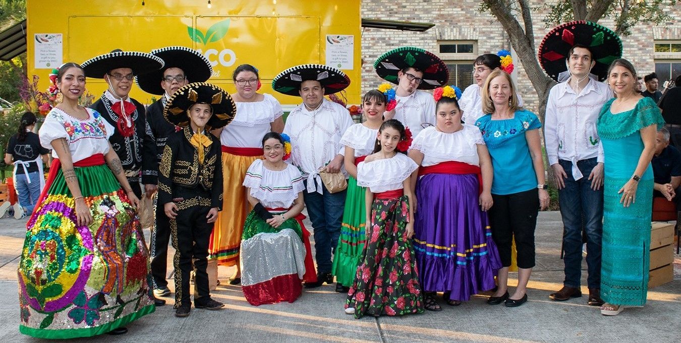 A group of people in traditional mexican clothing are posing for a picture.