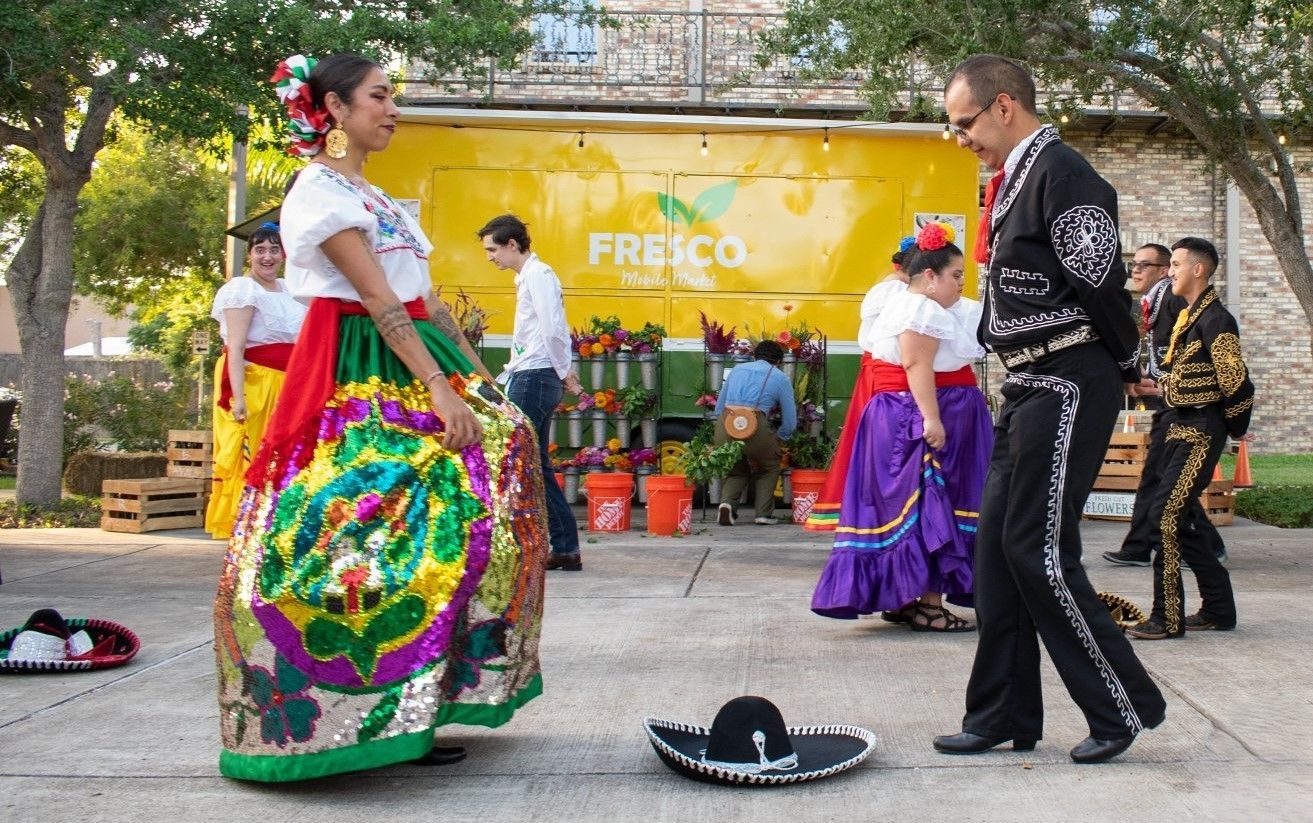 A group of people are dancing in front of a truck that says fresco