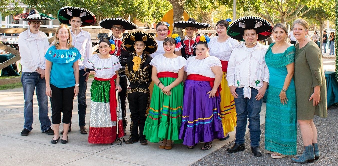 A group of people dressed in traditional mexican costumes are posing for a picture.