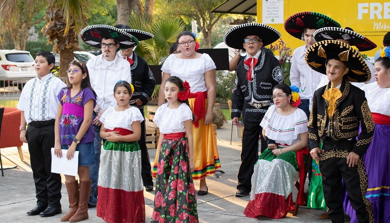 A group of people dressed in traditional mexican clothing are singing a song.