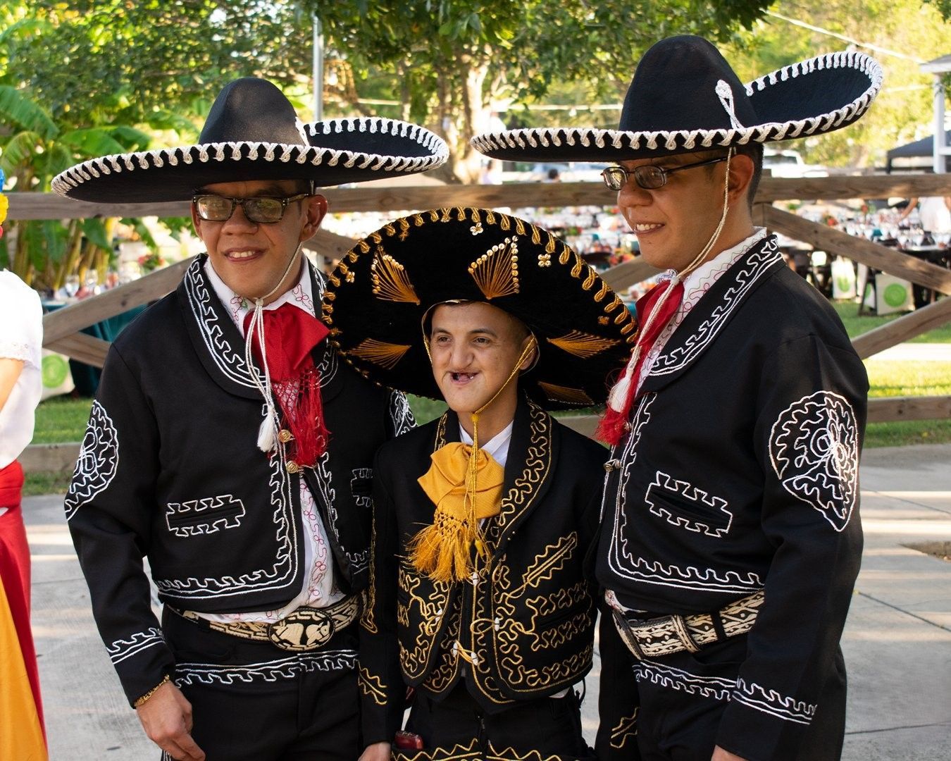 Three men in mariachi costumes are posing for a picture