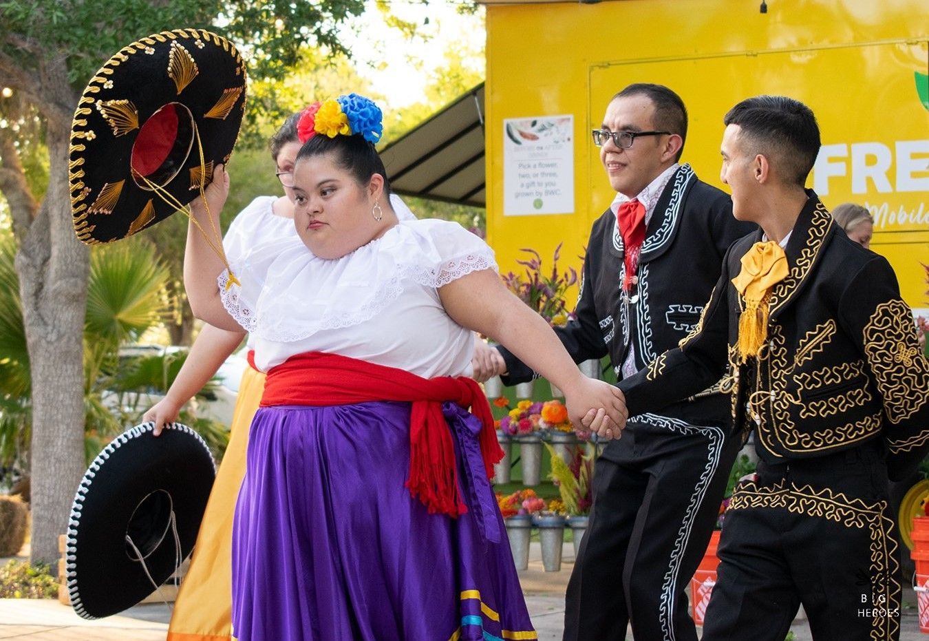 A group of people are dancing in front of a yellow truck that says free