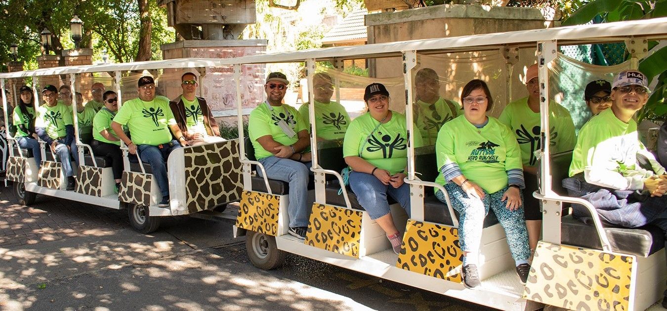 A group of people wearing green shirts are sitting on a trolley.