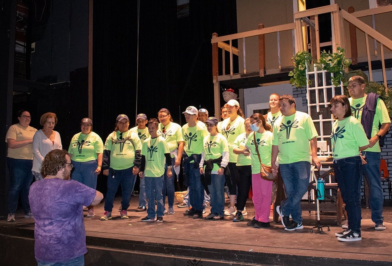 A group of people standing on a stage wearing green shirts with a cross on them