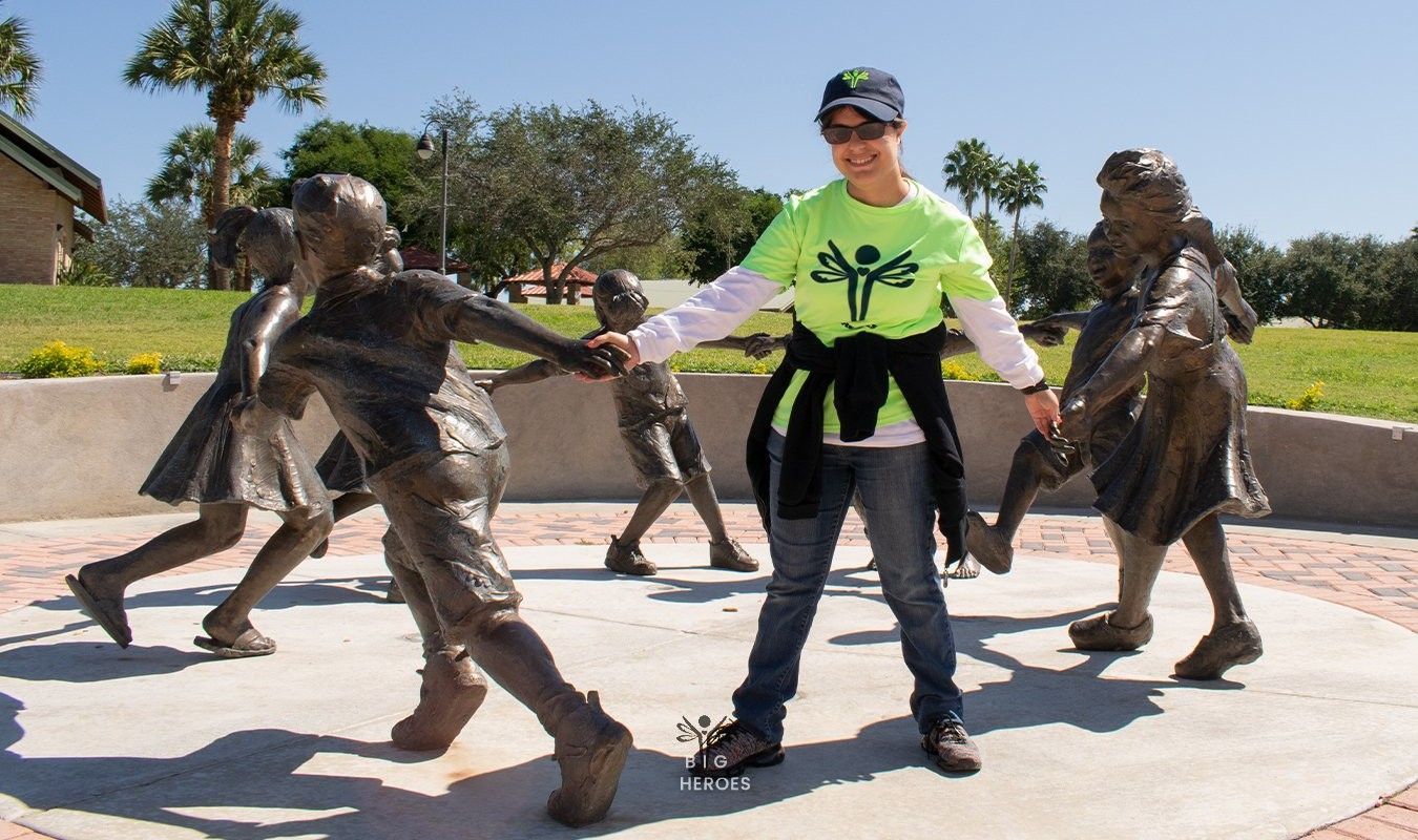 A woman in a green shirt is standing in front of a group of statues.
