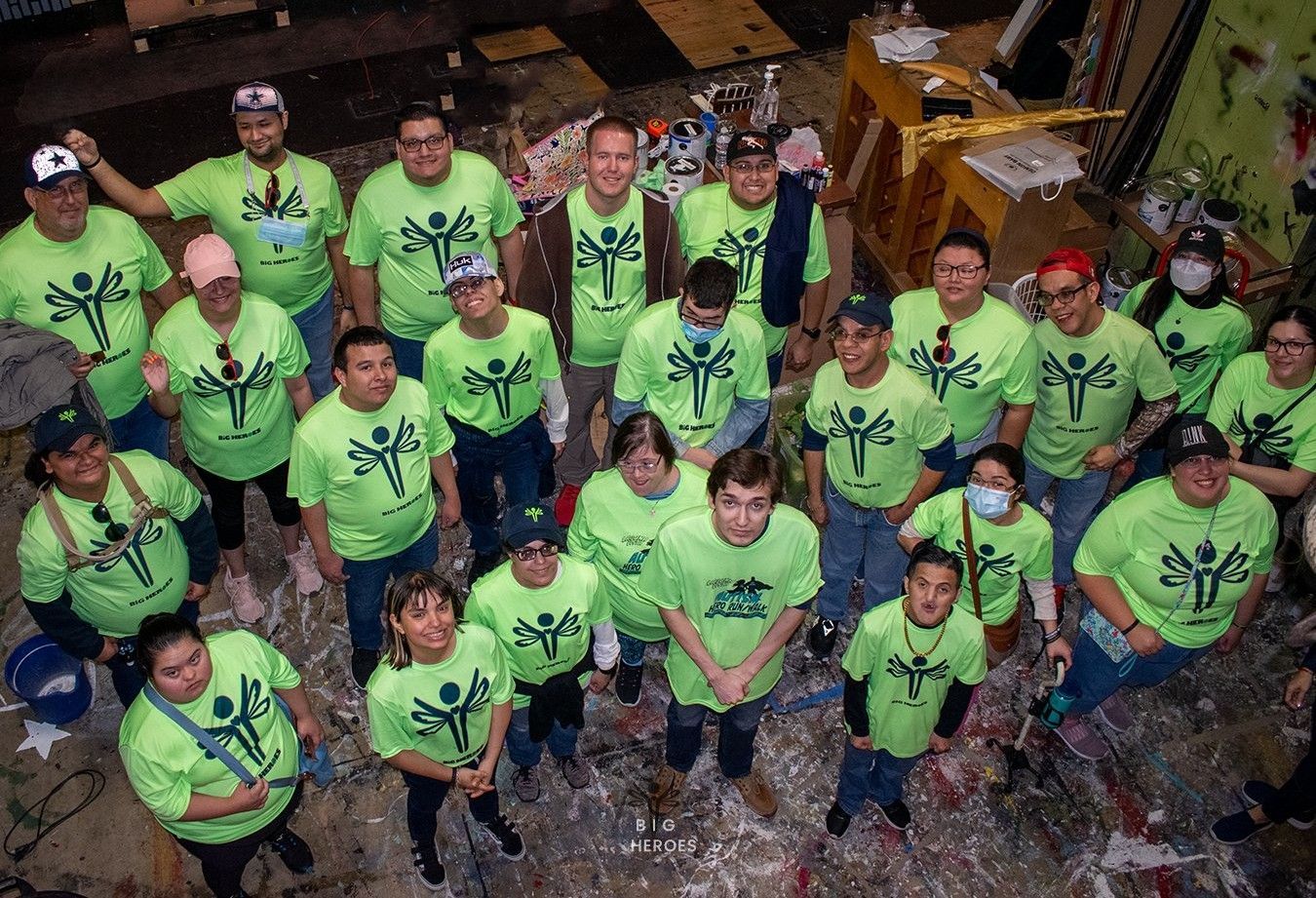 A group of people wearing green shirts are posing for a picture.