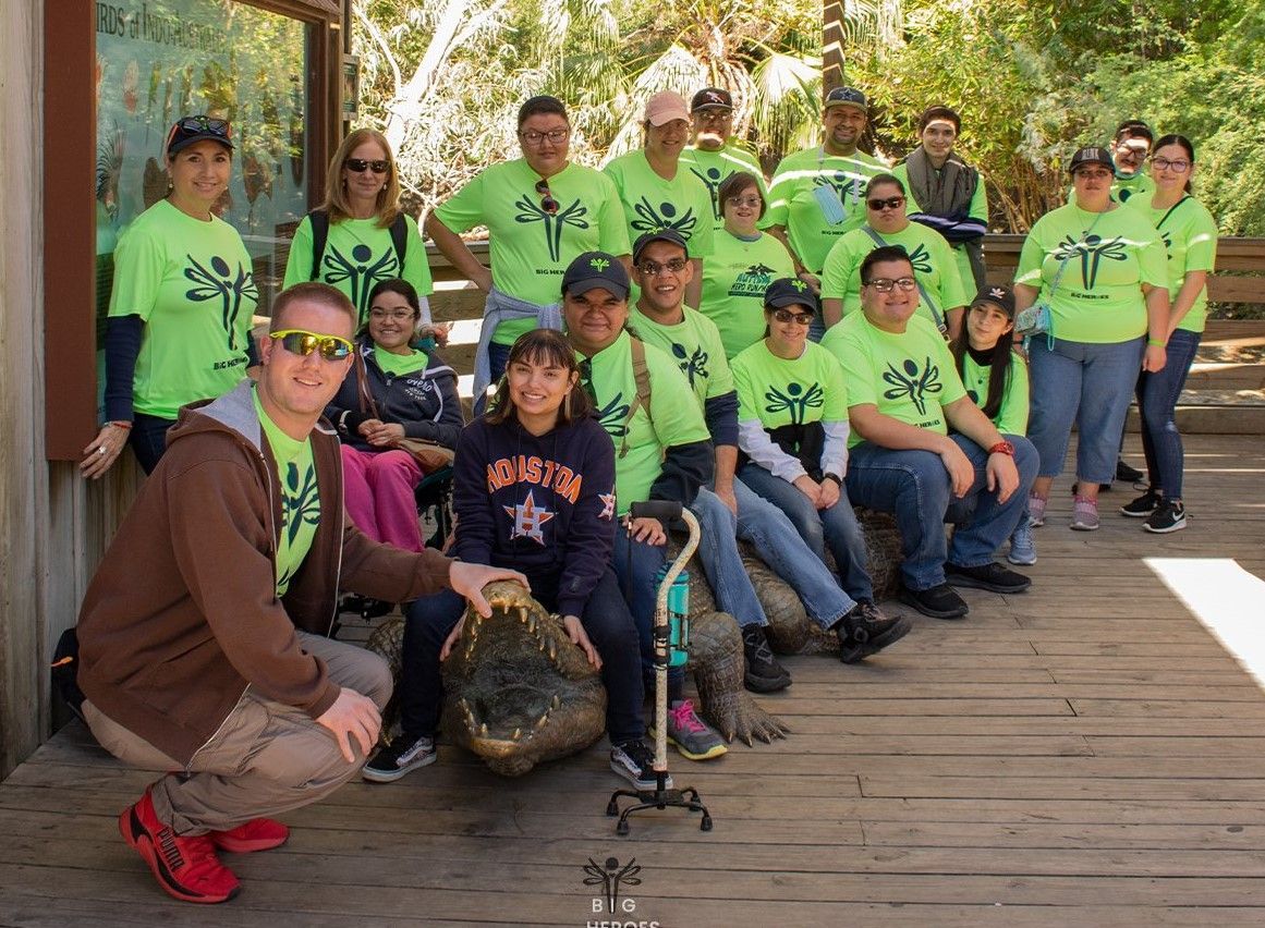 A group of people wearing green shirts are posing for a picture.