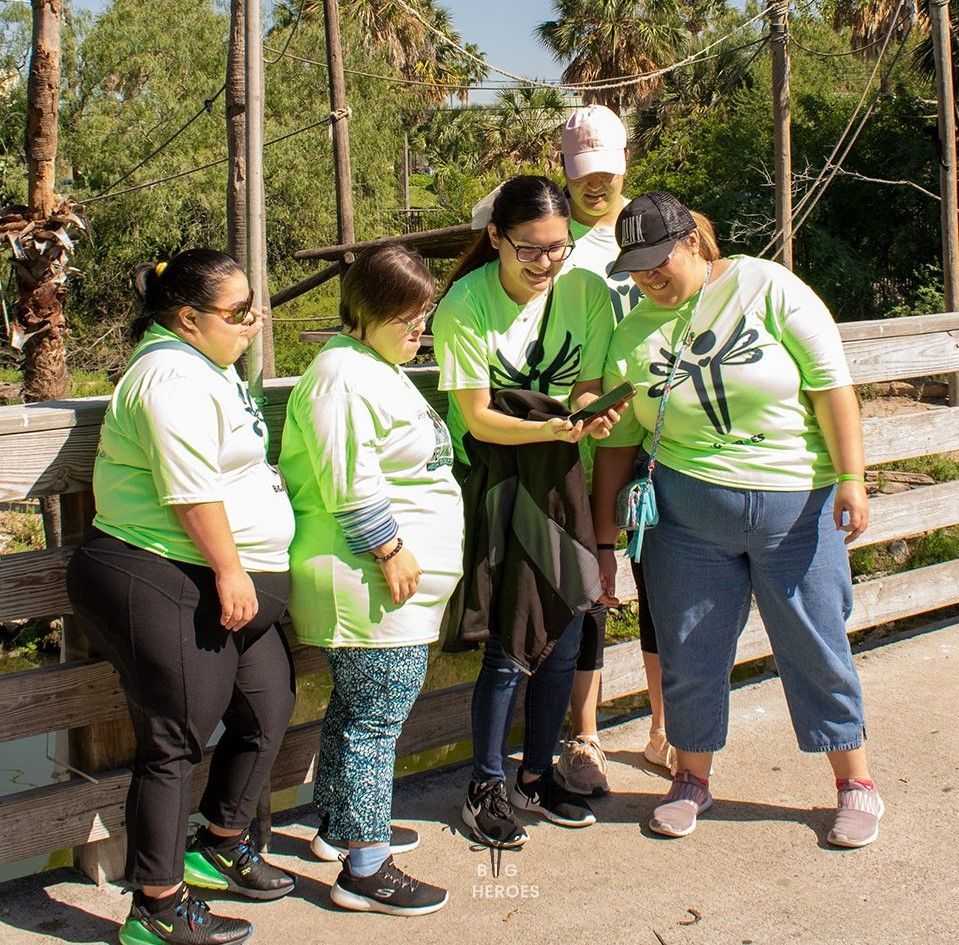 A group of women in green shirts are looking at a cell phone