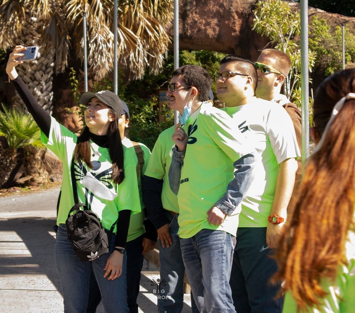 A group of people in green shirts are taking a selfie