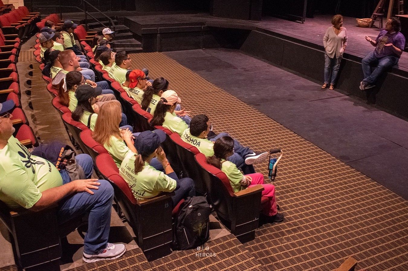 A group of people are sitting in a theater watching a play.