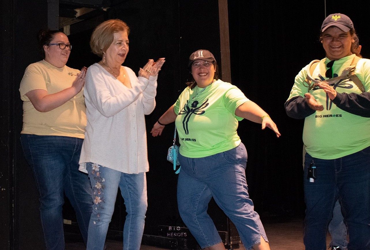 A group of people wearing green shirts are standing on a stage