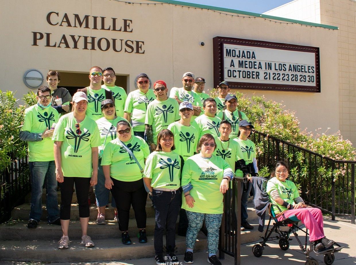 A group of people standing in front of camille playhouse