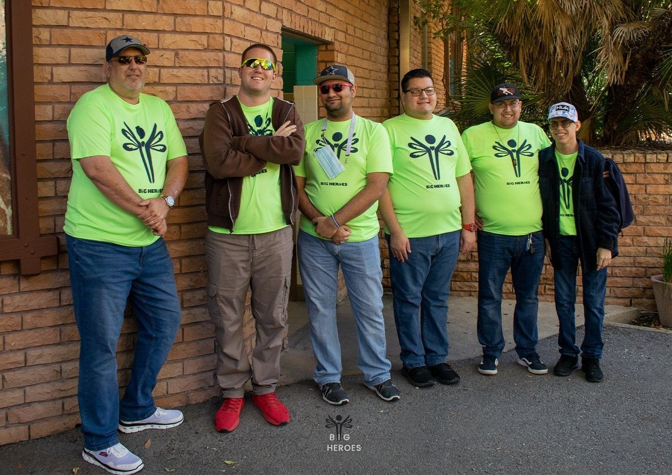 A group of men are posing for a picture in front of a brick building.