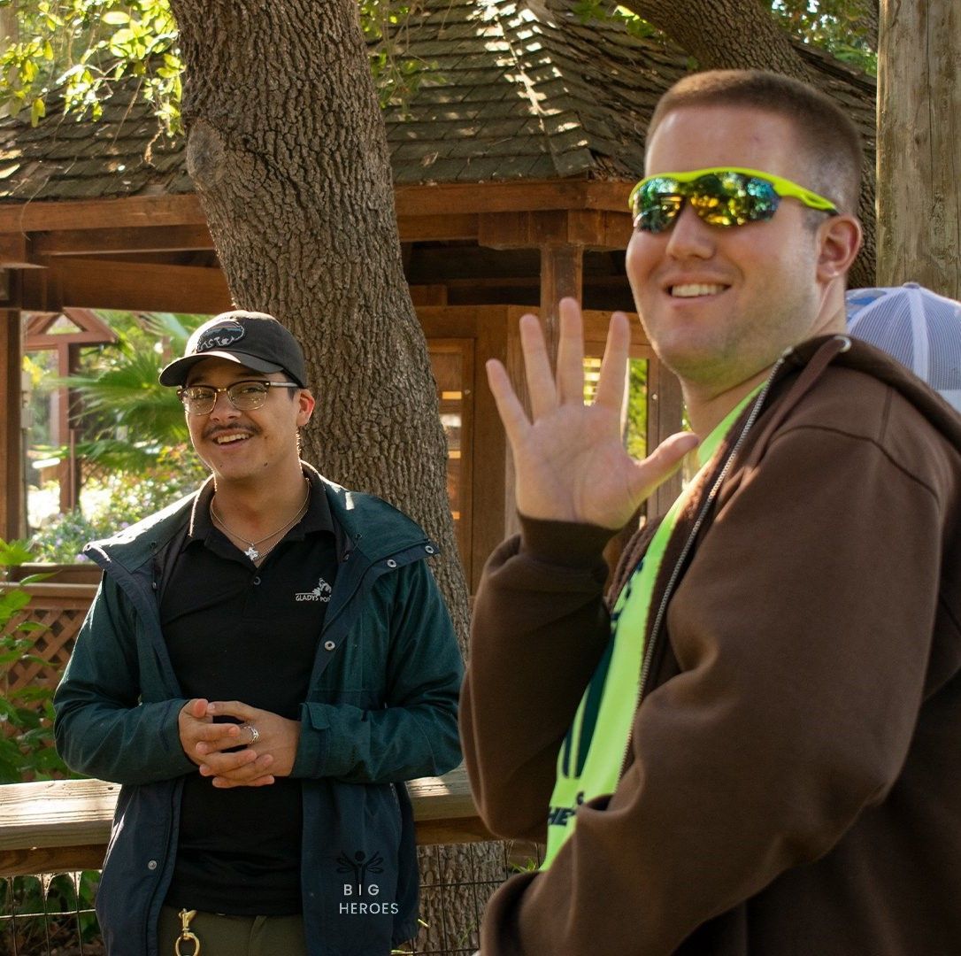 A man wearing sunglasses stands next to another man