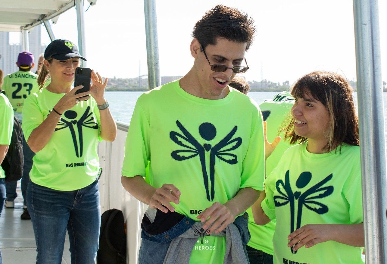 A group of people wearing neon green shirts with dragonflies on them are standing on a boat.