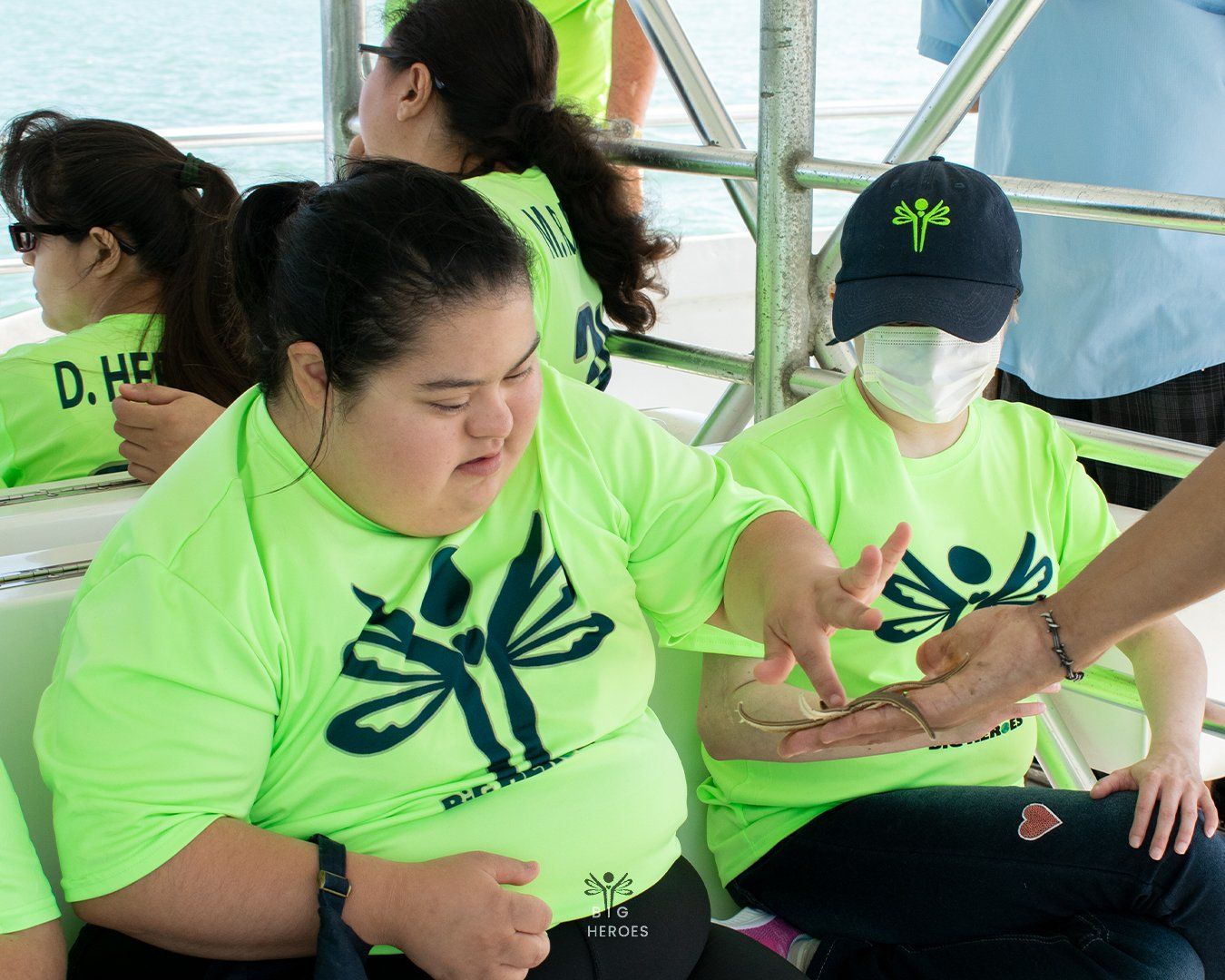 A group of people wearing neon green shirts are sitting on a boat