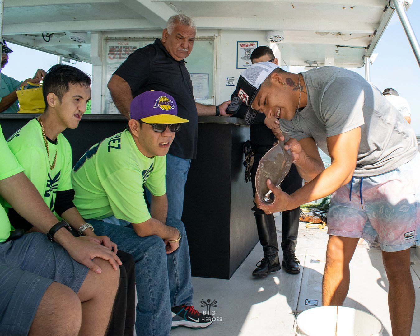 A group of people are sitting on a boat and a man is holding a fishing hook.