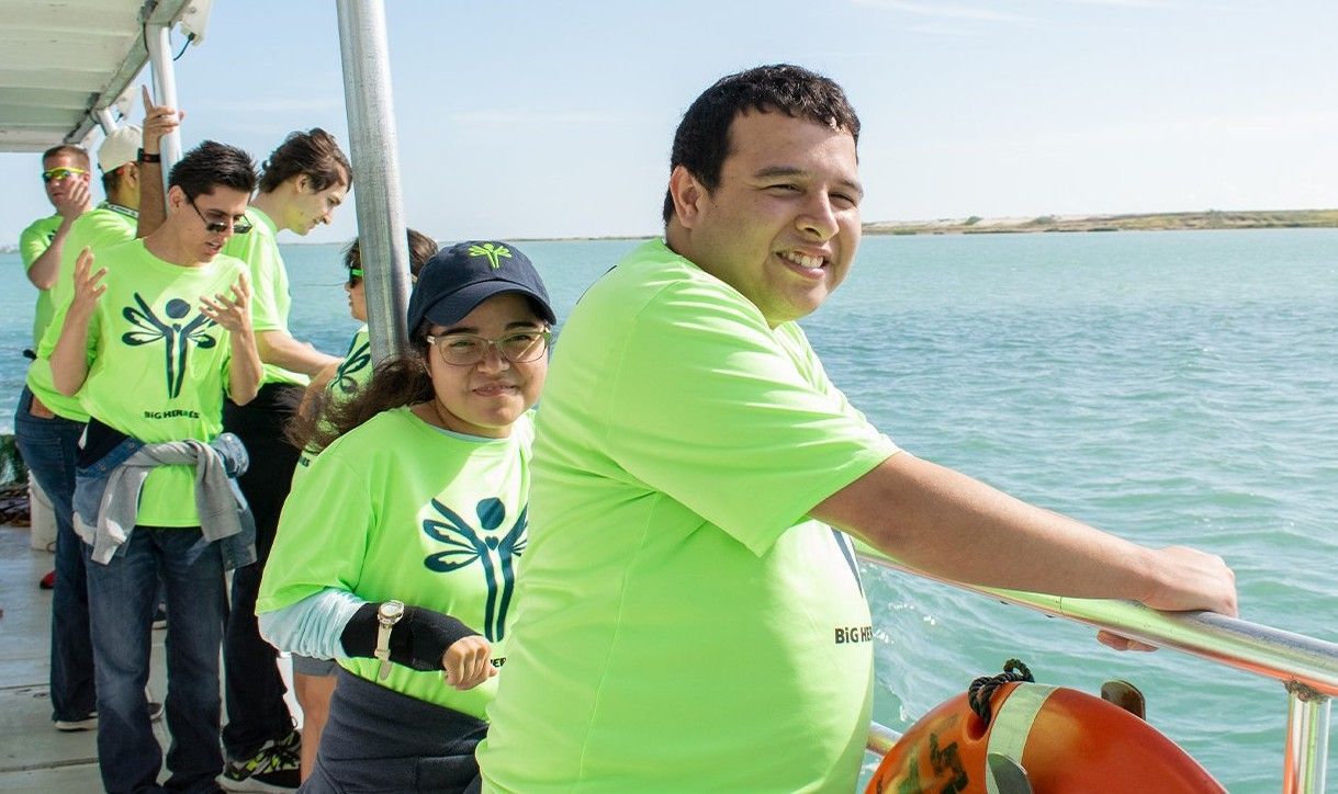 A group of people in green shirts are standing on a boat.