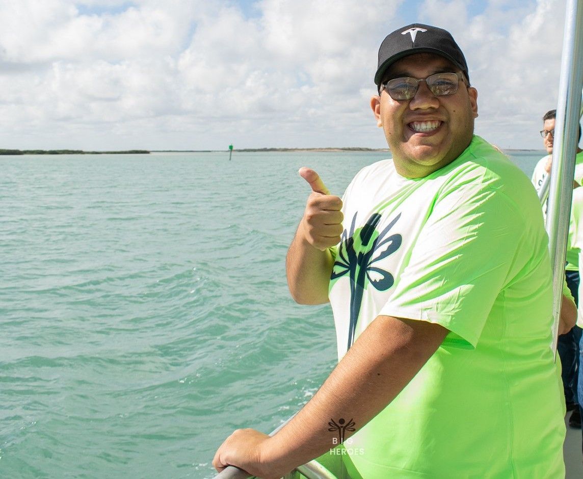 A man in a green shirt is giving a thumbs up on a boat