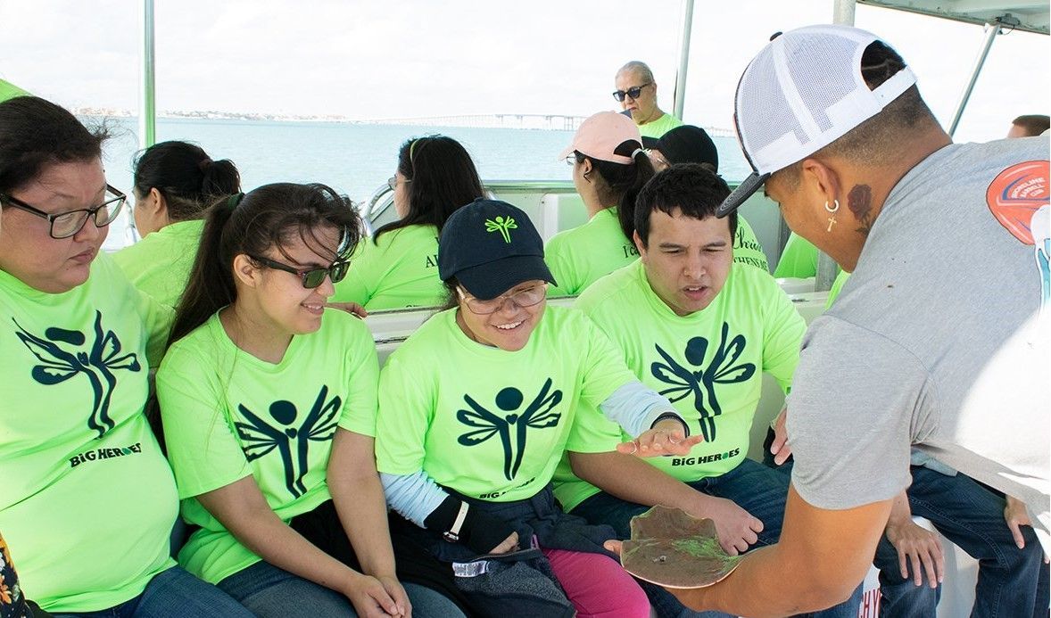 A group of people wearing green shirts are sitting on a boat.