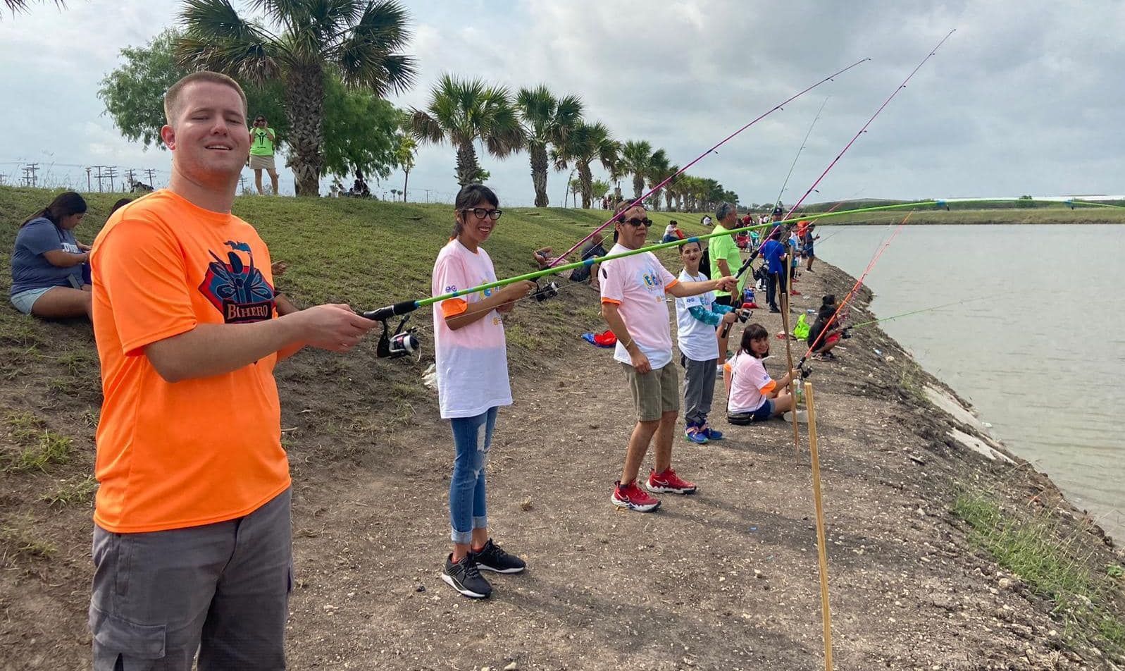 A group of people are fishing on the shore of a lake.