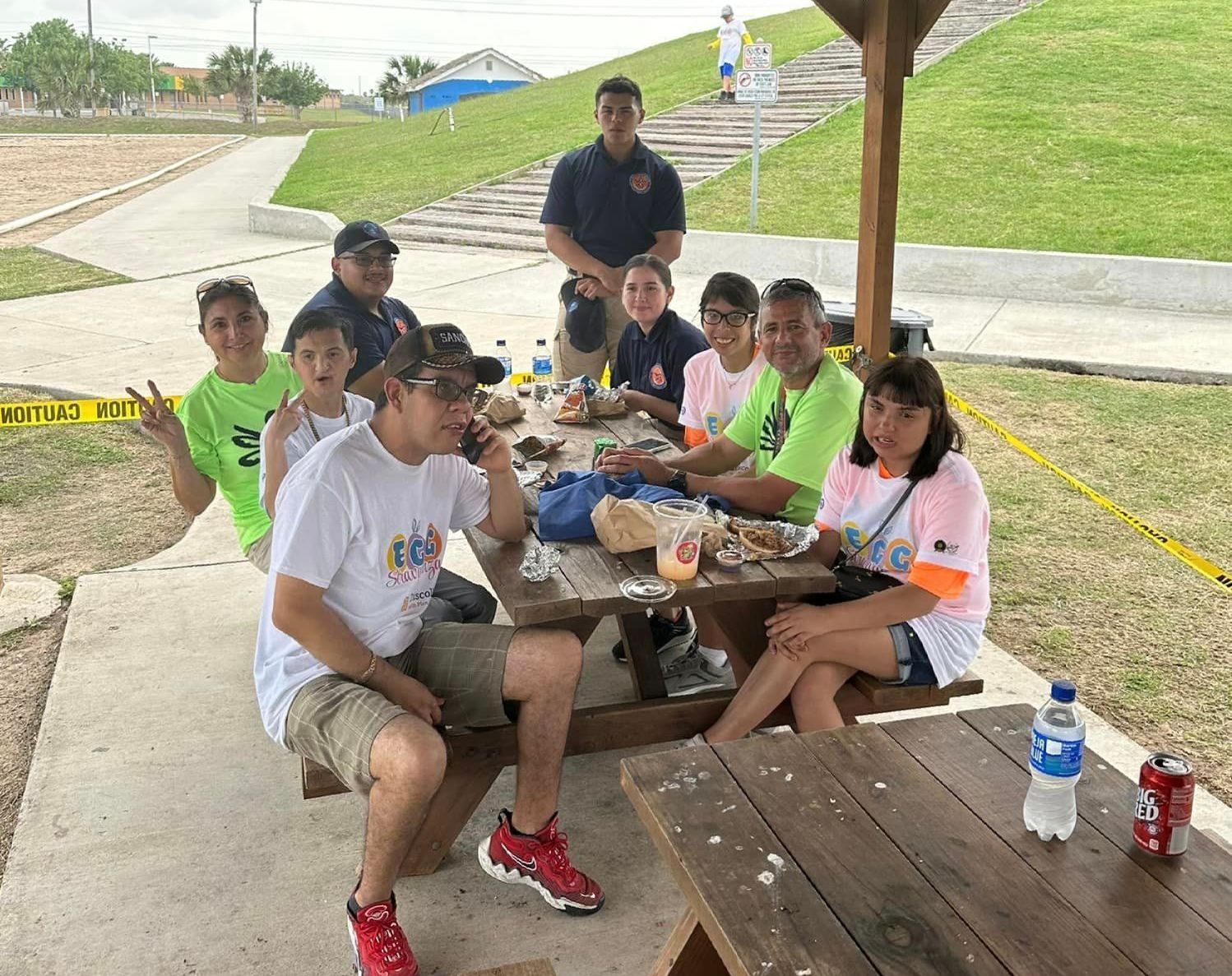 A group of people are sitting at a picnic table in a park.