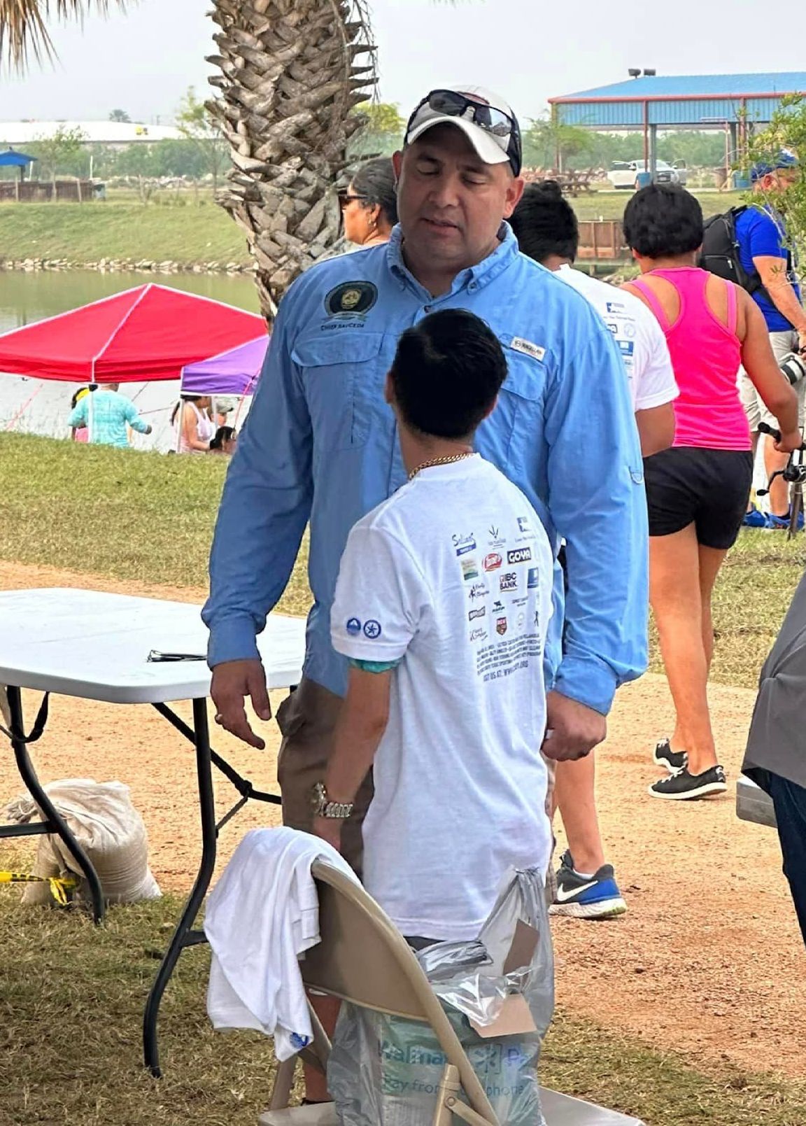 A man and a boy are standing next to each other in a park.