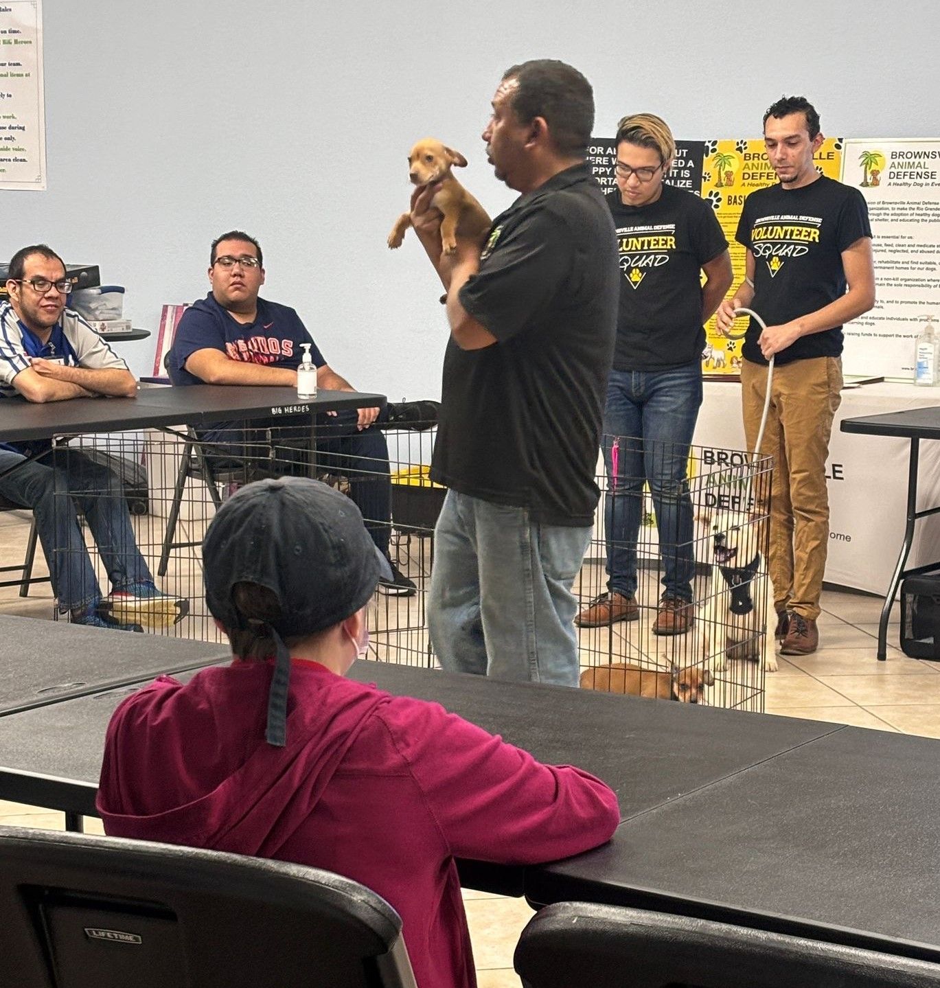 A man is holding a puppy in front of a group of people