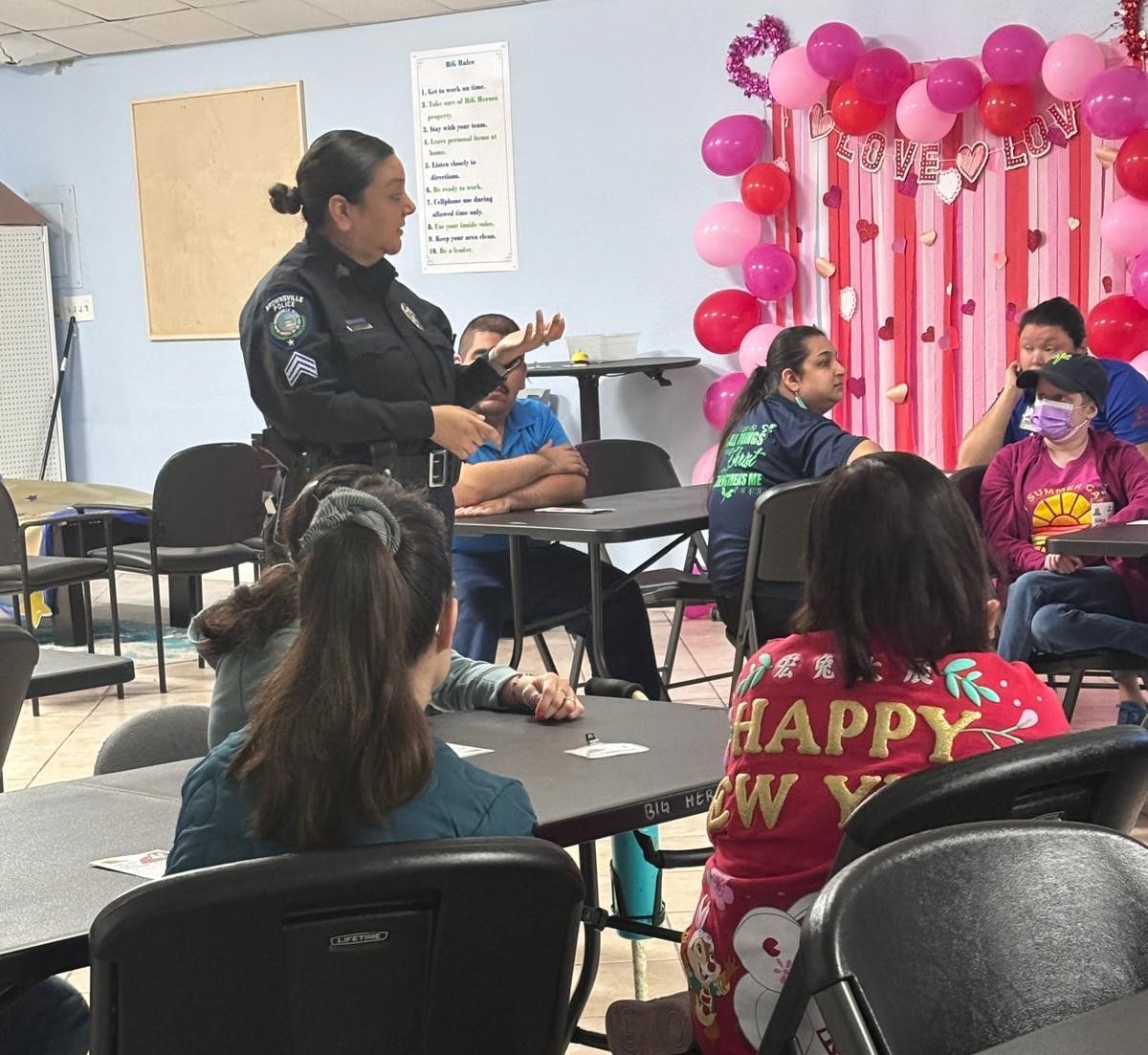 A woman is talking to a group of people sitting at tables.