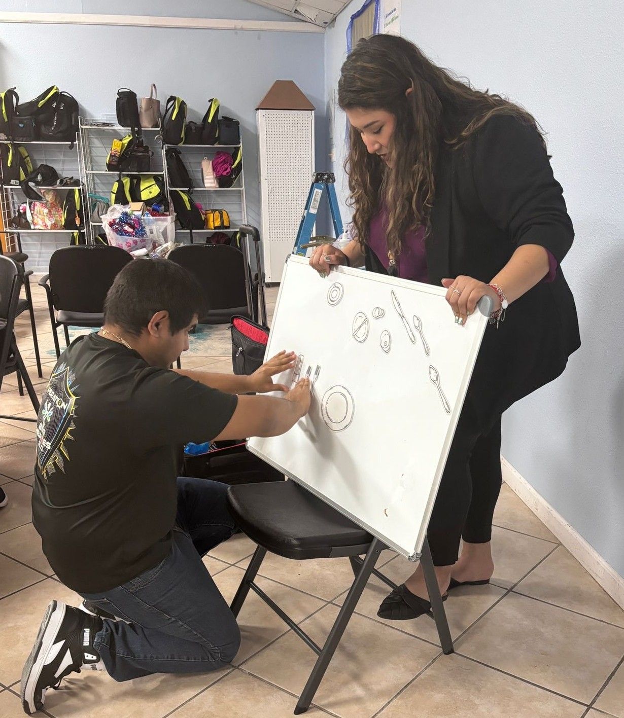 A man and a woman are writing on a white board