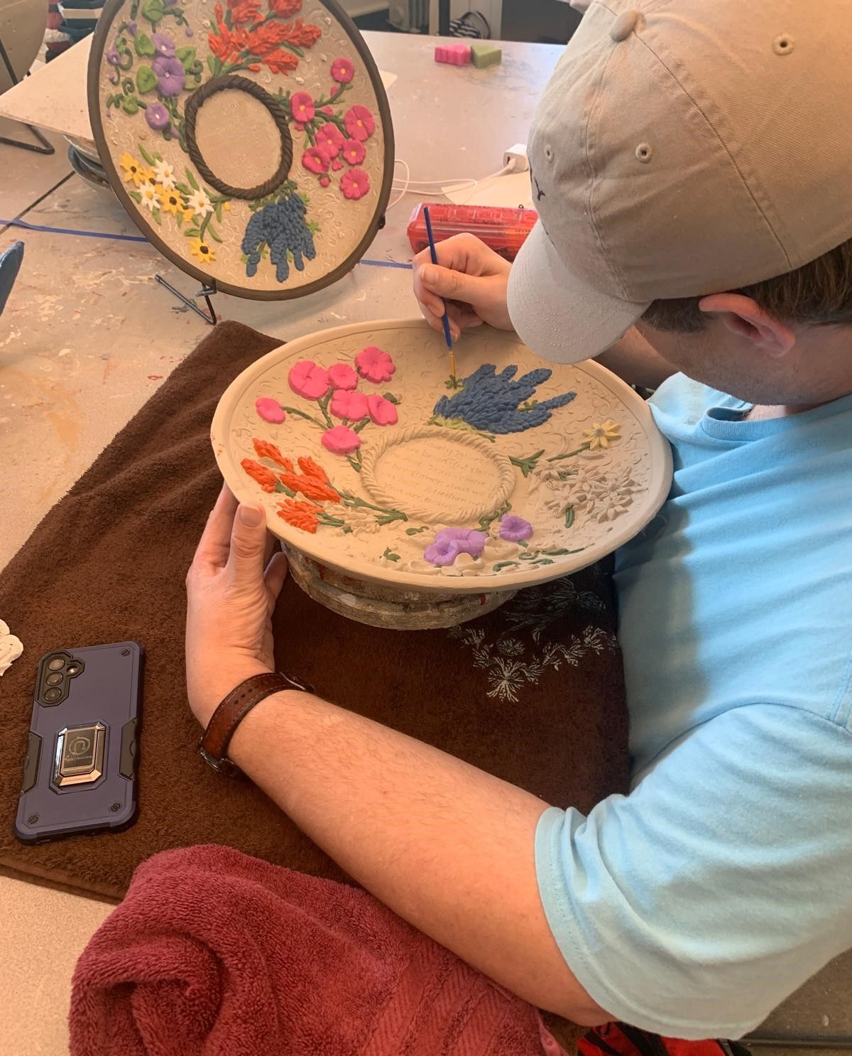 A man is painting a plate with flowers on it