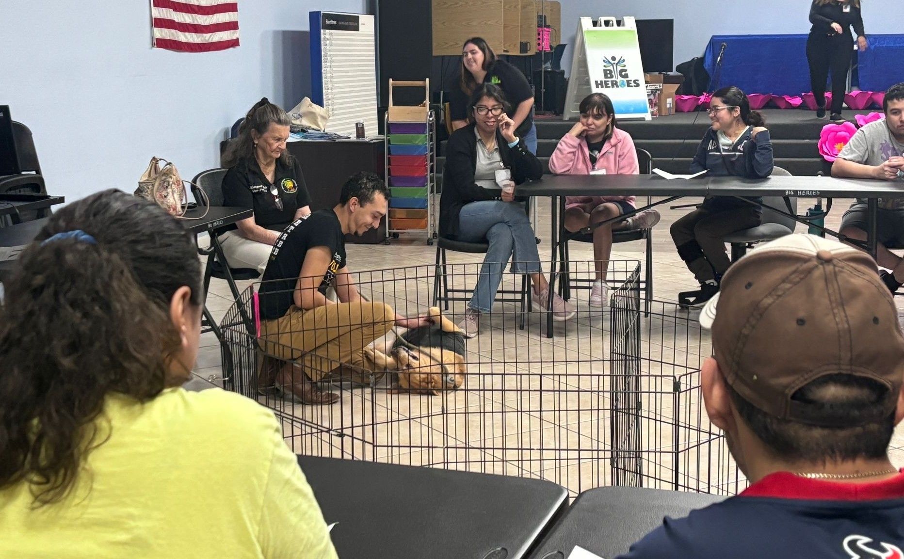 A group of people are sitting around a table with a dog in a cage.