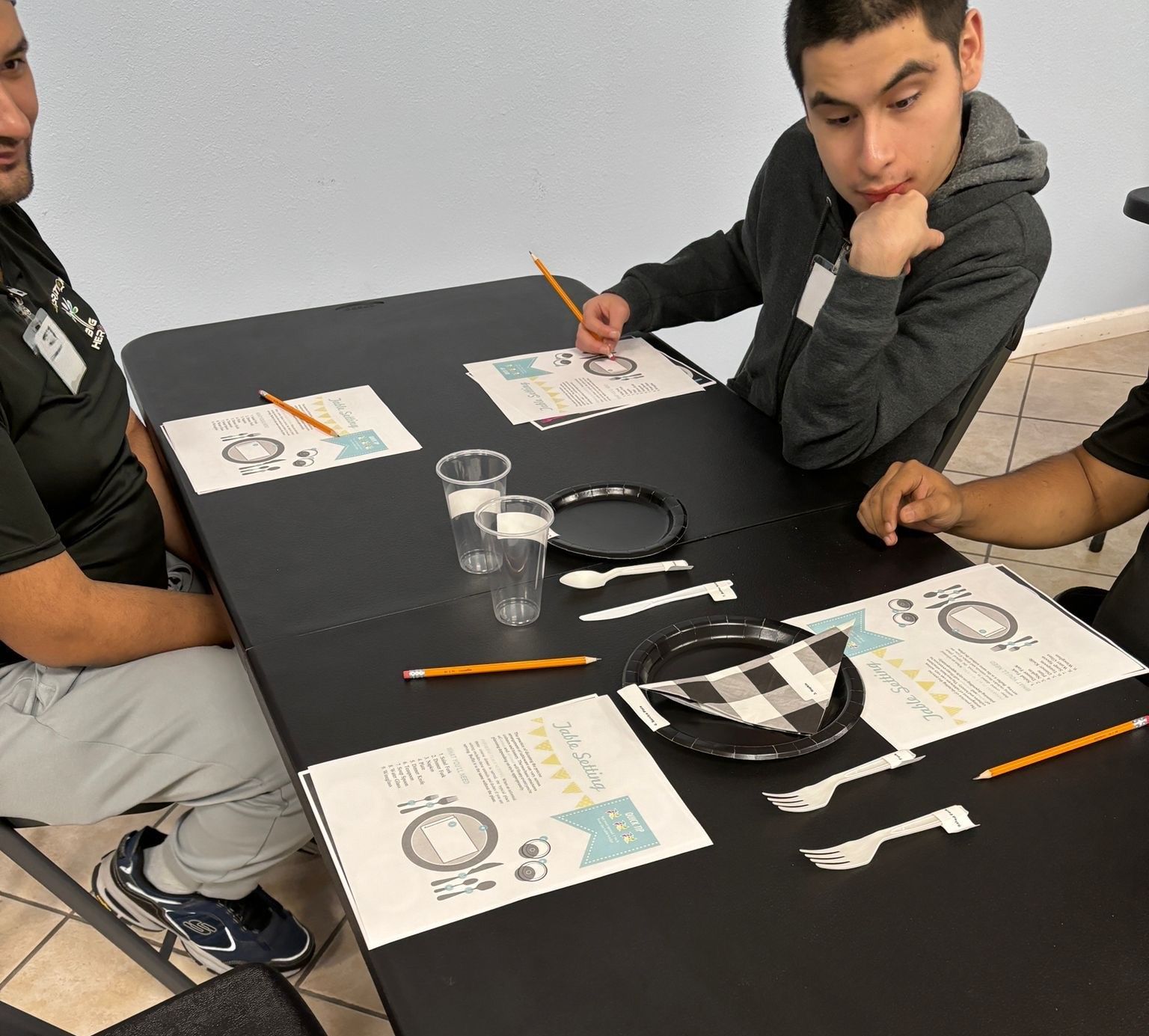 Three men are sitting at a table with plates and napkins on it